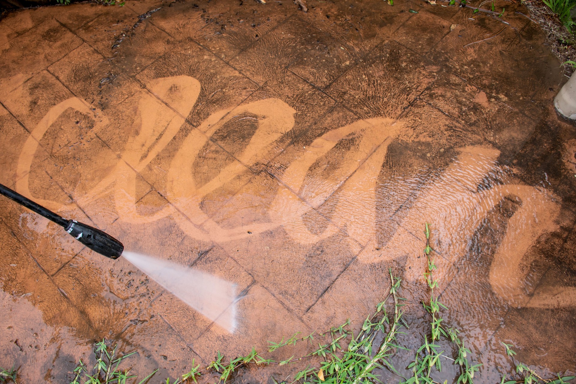Cleaning backyard paving tiles with pressure washer.